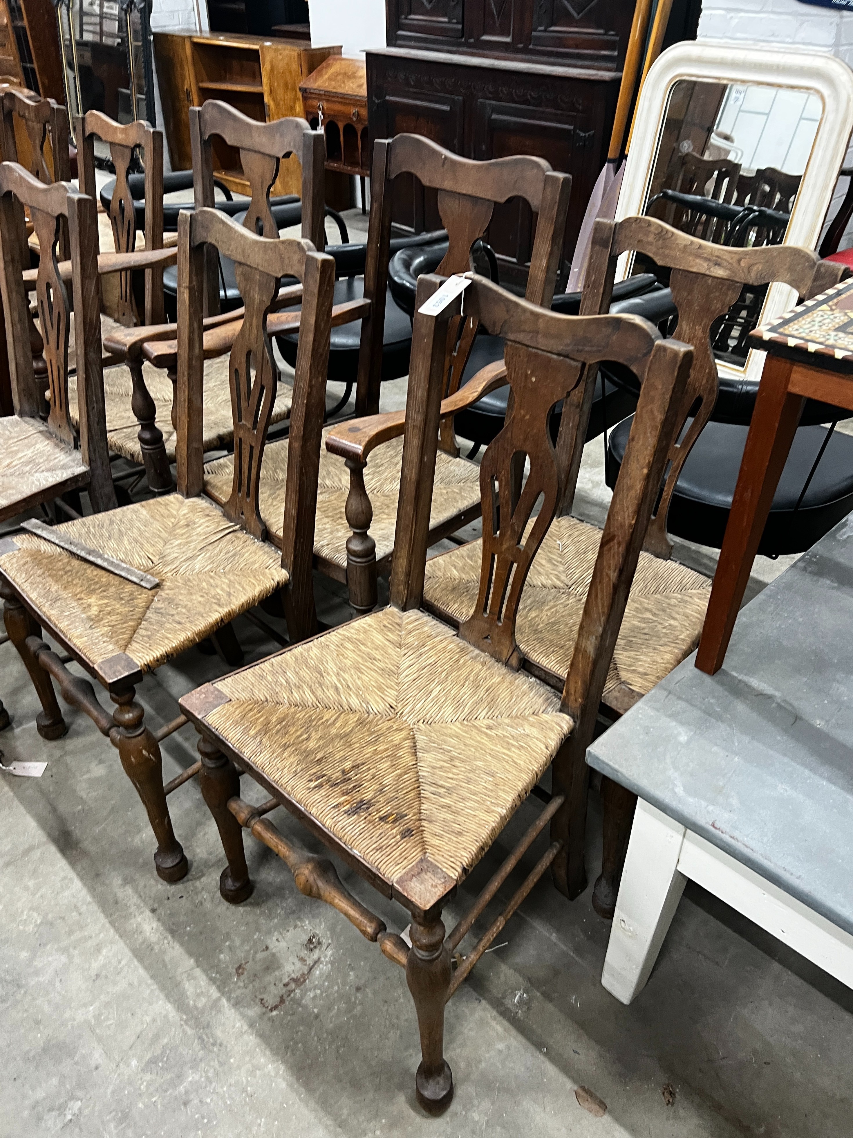 A set of ten George III style provincial oak rush seat dining chairs, two with arms.